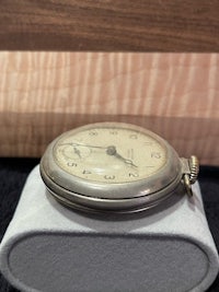 a silver pocket watch sitting on top of a box