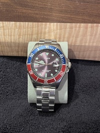 a watch with a red, blue, and silver bezel