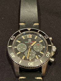 a watch with a black dial on a black leather strap