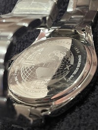 a close up of a silver watch with a globe on it