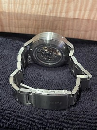 a stainless steel watch on a black cloth