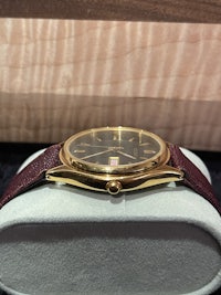 a gold and burgundy watch sitting in a box