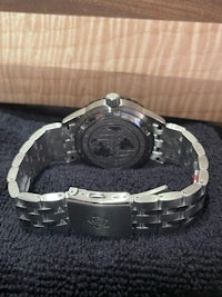 a stainless steel watch on a black cloth