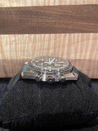 a black and silver watch sitting on a wooden table