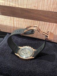 a watch with a rose gold band on a black cloth