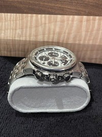 a silver watch is sitting on top of a wooden box