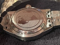 a silver watch with a world map on it