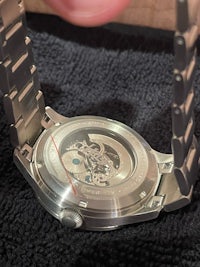 a person is holding a watch with a skeleton on it