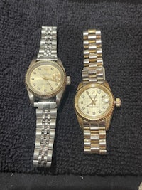 two rolex watches on a black cloth