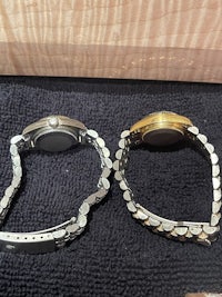 two watches sitting on a table next to each other