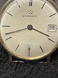 a gold watch with a black dial