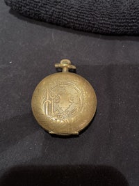 a small brass pocket watch on a black surface