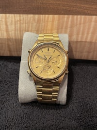 a gold watch sitting on a wooden table