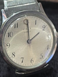 a silver watch on a black background