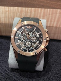 a rose gold and black watch sitting on a table