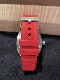 a watch with a red strap sitting on a table