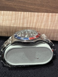 a watch with a red, blue, and silver dial sitting on top of a box