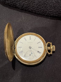 a gold pocket watch with roman numerals and roman numerals