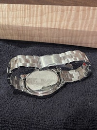 a silver watch on a piece of wood