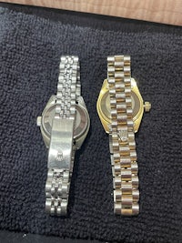 two watches on a table next to each other