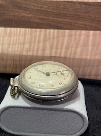 a pocket watch sitting on a table next to a cutting board