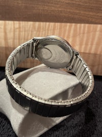 a silver watch with a black band sitting on a table