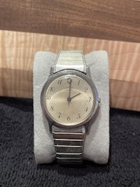 a silver watch sitting on a wooden table