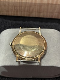 a gold watch sitting on top of a wooden box