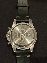 a silver watch on a black leather strap