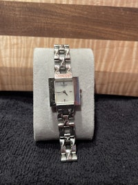 a silver watch sitting on a wooden surface