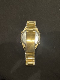 a gold watch sitting on a black surface