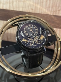 a black and gold watch sitting on a gold ring