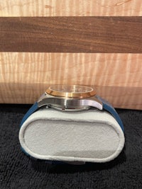 a watch with a blue leather case sitting on top of a cutting board