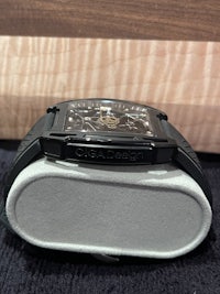 a black watch sitting on a table next to a box