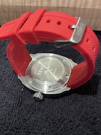 a watch with a red strap sitting on a table
