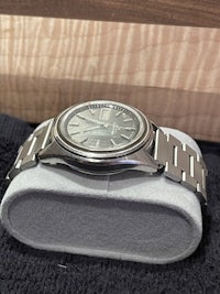a silver watch sitting on a wooden box