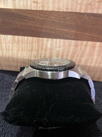 a stainless steel watch on a black background