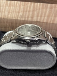 a silver watch sitting on a wooden box
