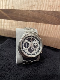 a silver watch sitting on top of a cutting board