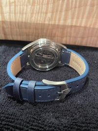 a watch with a blue leather strap