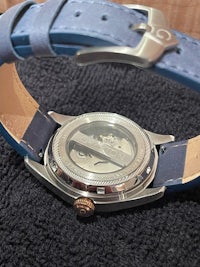 a watch with blue leather straps on a black background