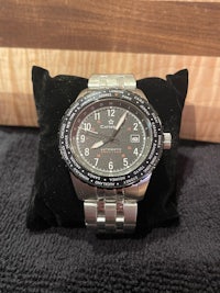a silver watch sitting on a black pillow
