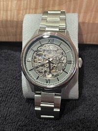 a silver watch with a skeleton on it