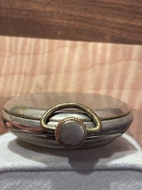 a silver pocket watch with a stone on it