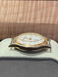 a gold watch sitting on a table in front of a box