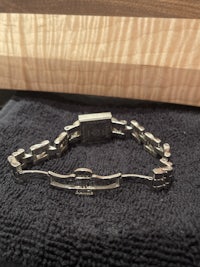 a silver bracelet is sitting on top of a piece of wood