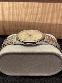 a silver watch sitting on a wooden box
