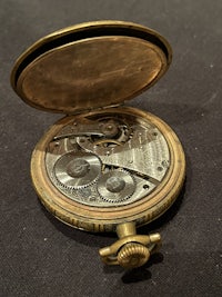 a gold pocket watch on a black surface