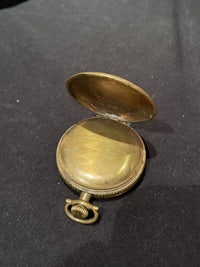 a small brass pocket watch on a black surface