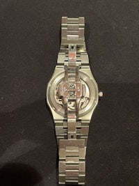 a silver watch on a black surface